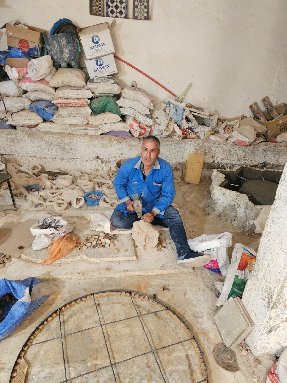 Abdelhafid Aït Touil taillant une pièce de zellige à la qaddoum dans son atelier